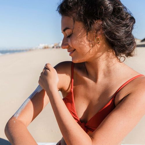 person applying sunscreen to arms and body